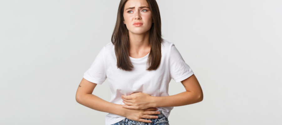 Gastrite: mulher com mãos na barriga a manifestar dor