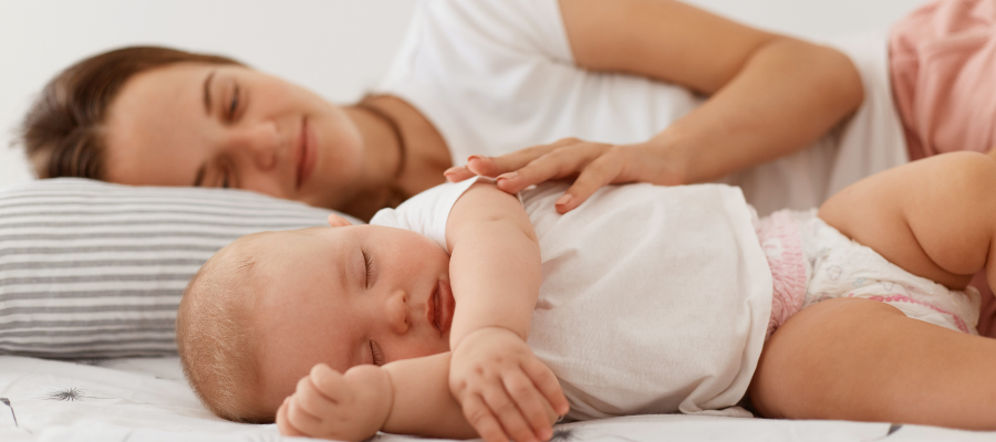 mãe e bebé deitados na cama a dormir