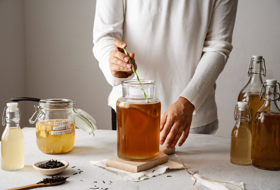 mulher com frascos de kombucha em cima da mesa a produzir este alimento fermentado