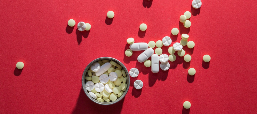 Frasco de aminoácidos em comprimido sobre fundo vermelho