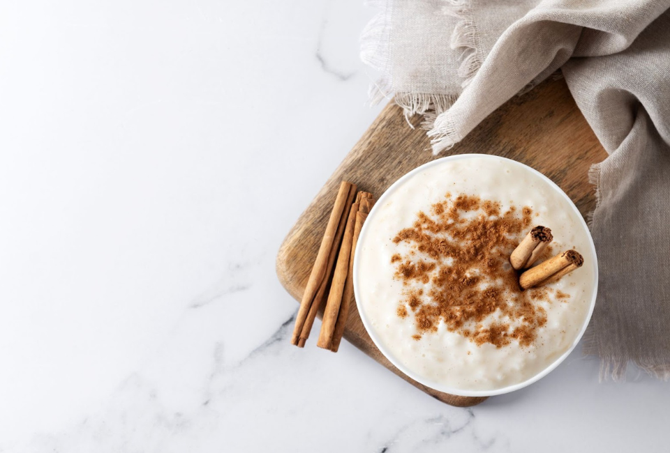 Taça de arroz doce polvilhado com canela e paus de canela a decorar