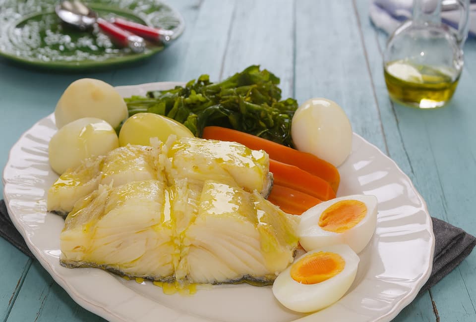 Travessa com postas de bacalhau, ovo cozido, batatas, cenouras e couve