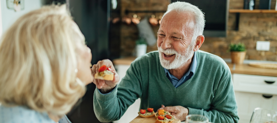 Senhor de terceira idade com ar feliz a partilhar a refeição com mulher