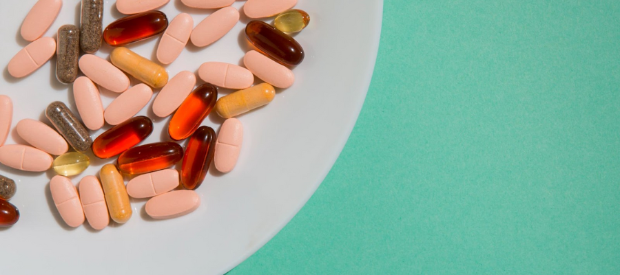 Prato branco com suplementos alimentares em comprimidos sobre fundo verde