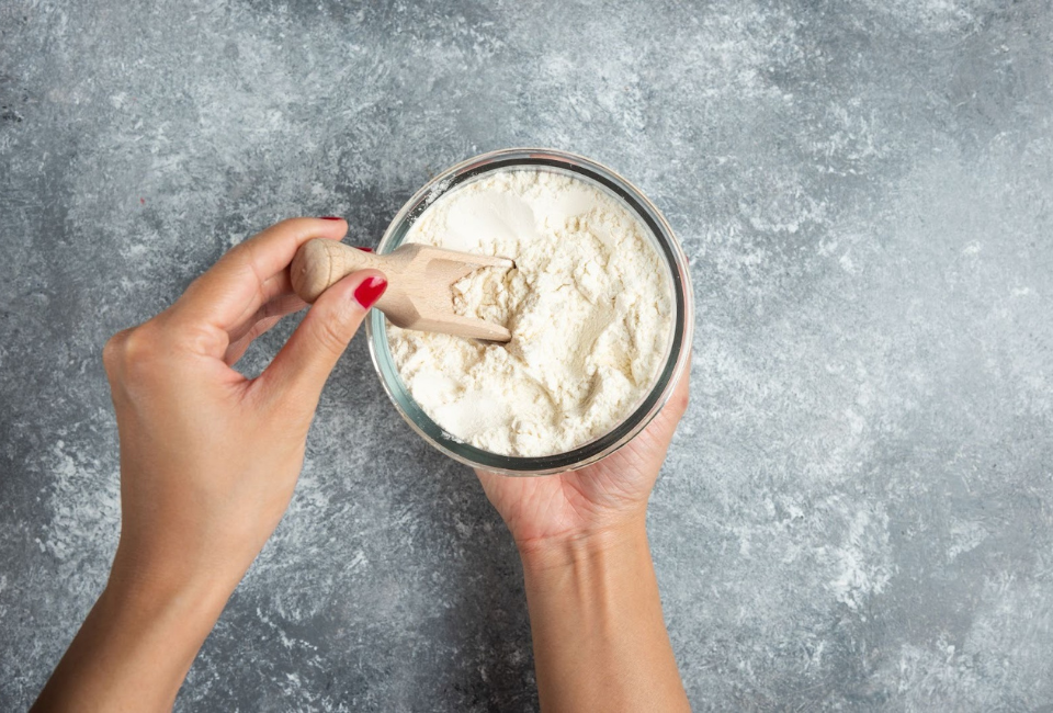 Senhora a tirar uma colher de creatina em pó de um frasco
