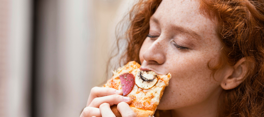 Mulher a comer uma fatia de pizza de olhos fechados