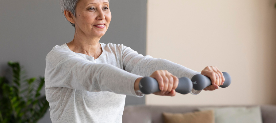 Senhora com dois halteres nas mãos a fazer exercícios para fortalecer ossos e articulações