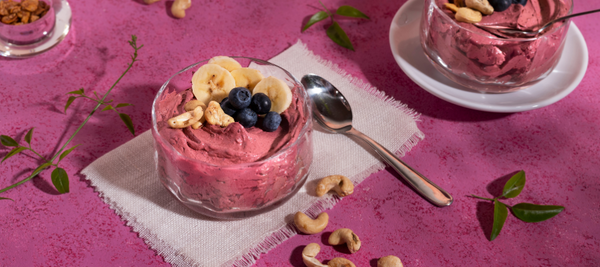 Taças de gelado de morango decoradas com bananas, mirtilos e caju