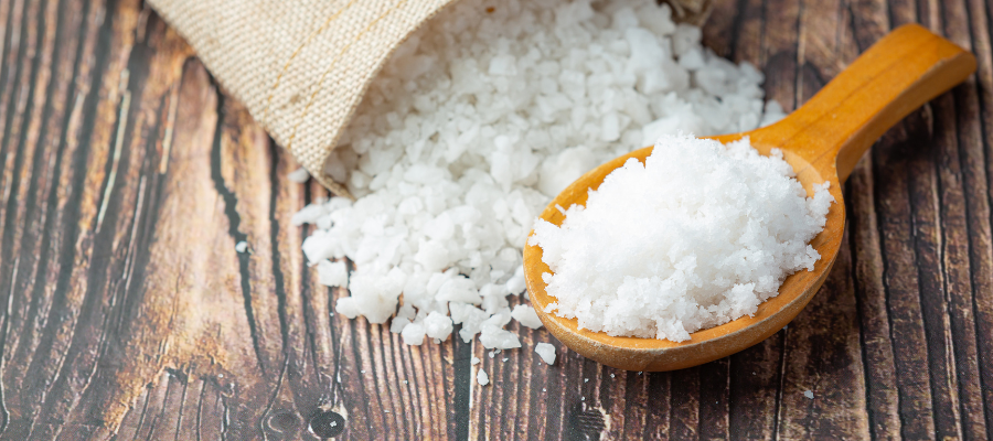 Saco aberto de sal com uma colher de madeira com o mesmo sal