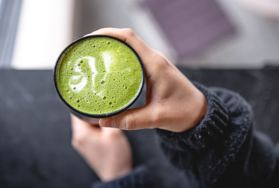 Pessoa a segurar num copo com matcha latte