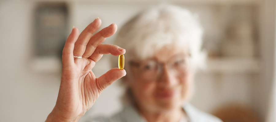 mulher a segurar numa pequena cápsula de ómega-3