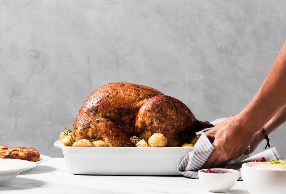 Pessoa a servir travessa com peru recheado no forno