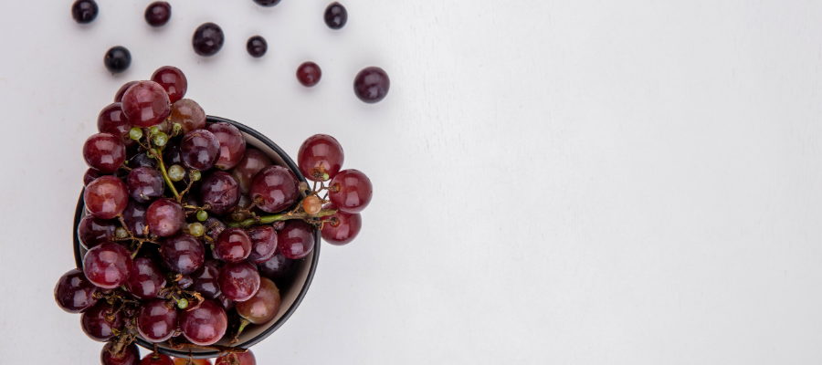 Taça de uvas vermelhas vista de cima em fundo branco